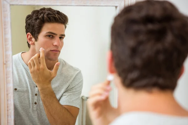Man applying moisturizer on face