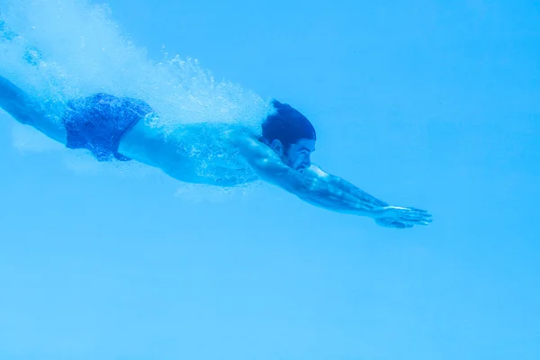 Man swimming underwater in swimming pool