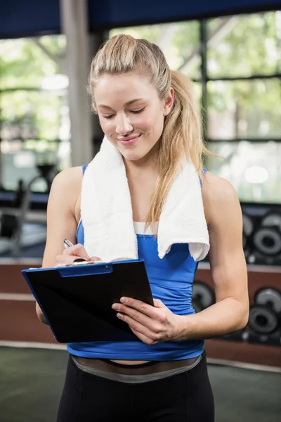 Gym instructor writing on clipboard