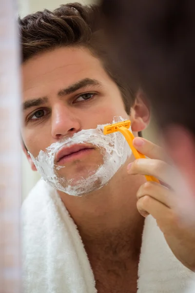 Man shaving in front of bathroom mirror
