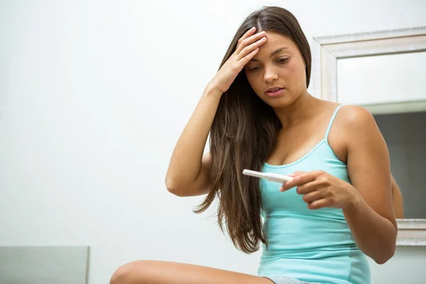 Worried woman looking at pregnancy test