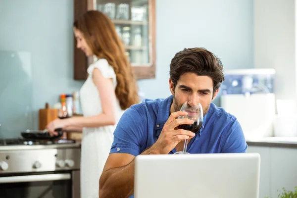 Man having red wine using laptop