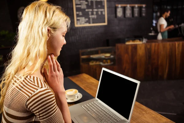 Woman drinking coffee and using laptop