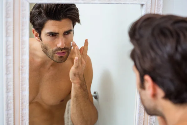 Man applying moisturizer on face