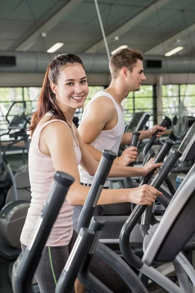 Woman and man exercising on elliptical machine