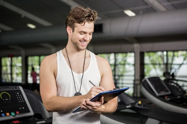 Gym instructor writing on clipboard