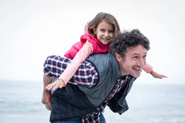 Father piggybacking daughter at beach