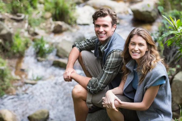 Hikers sitting on rock by stream