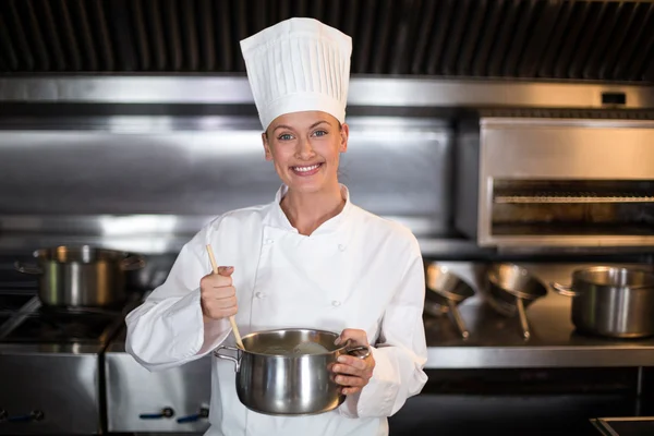 Chef holding saucepan in commercial kitchen