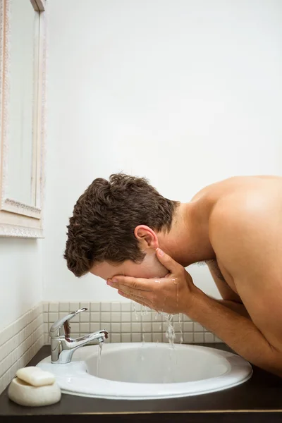 Man washing his face in  bathroom