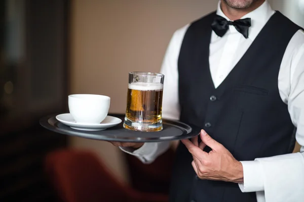 Waiter holding tray with beer
