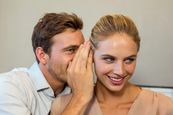 Man whispering to female colleague