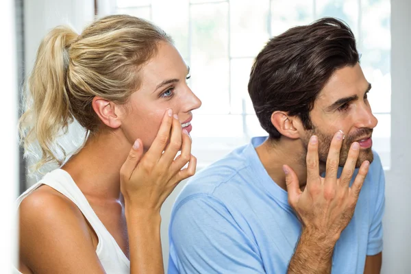 Man and woman applying moisturizer on face