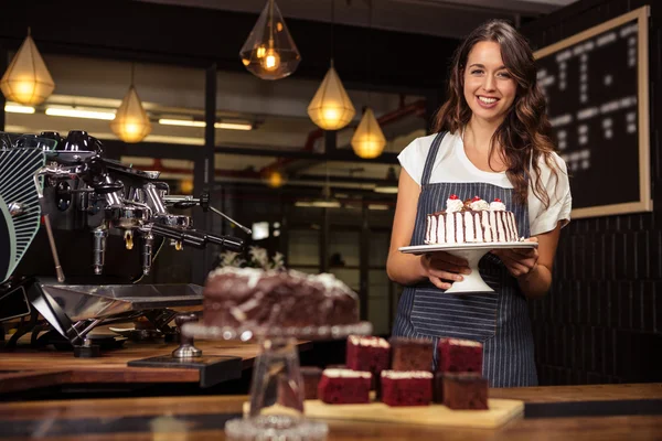 Barista holding plate with cake