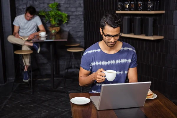 Man using a laptop and drinking coffee