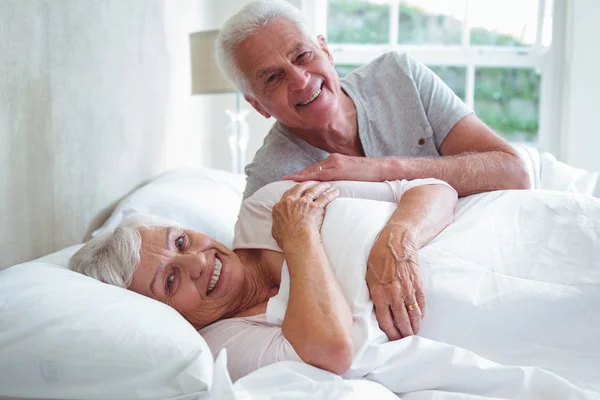Portrait of smiling senior couple relaxing on bed