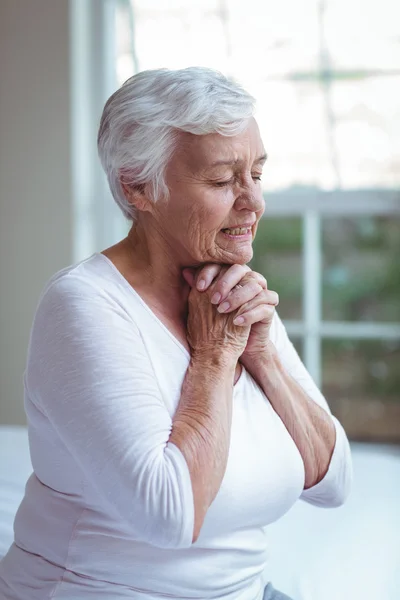 Senior woman praying at home