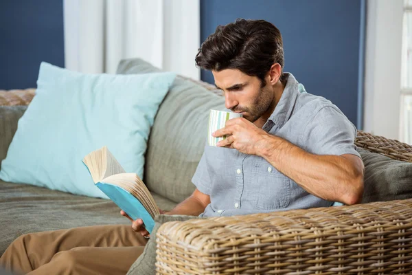 Man having coffee while reading book