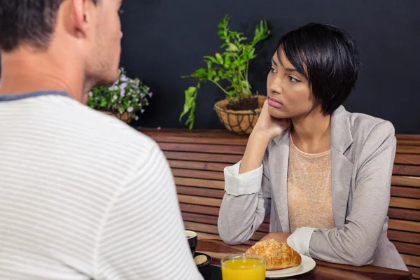 Unhappy woman sitting in front of boyfriend