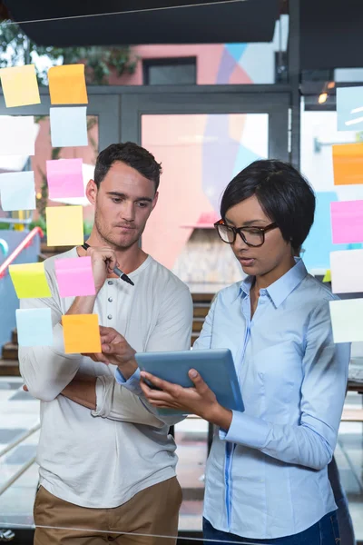 Colleagues looking at sticky notes and tablet