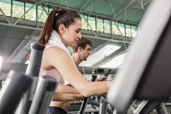 Woman and man exercising on elliptical machine