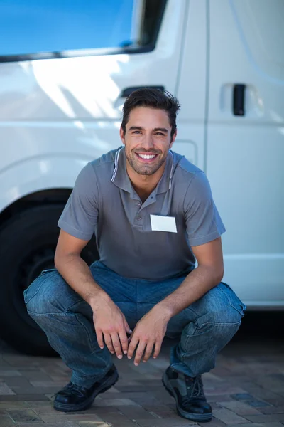 Delivery man crouching by van