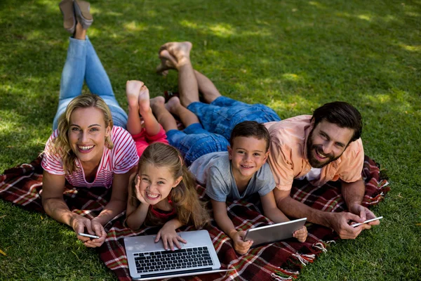 Family using technologies while lying in yard