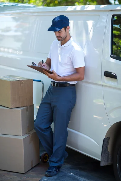 Delivery man writing in clipboard