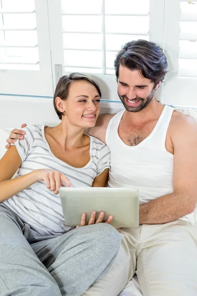 Couple using digital tablet on bed