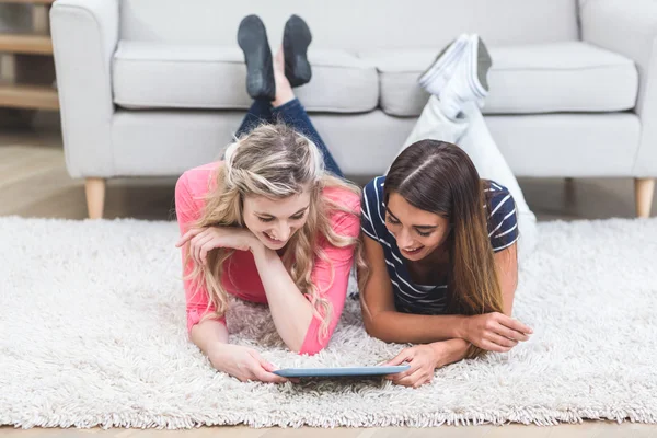 Women lying on rug and using tablet