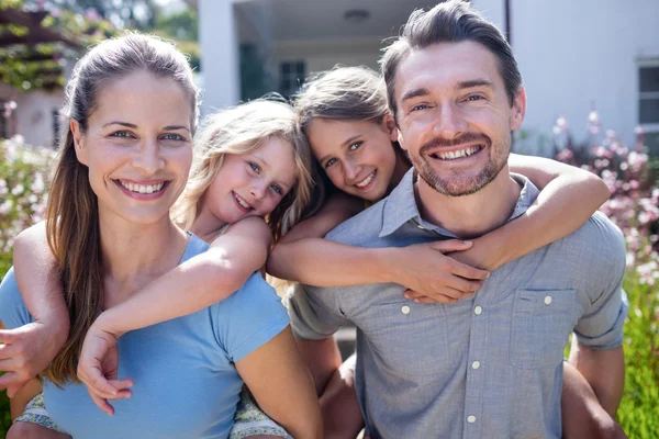 Parents giving piggy back to daughters