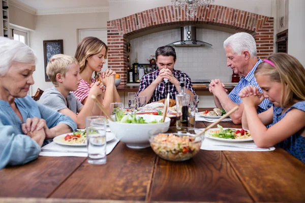 Family praying before having meal