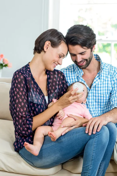 Parents feeding milk to daughter