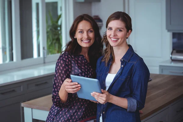 Women using digital tablet in kitchen