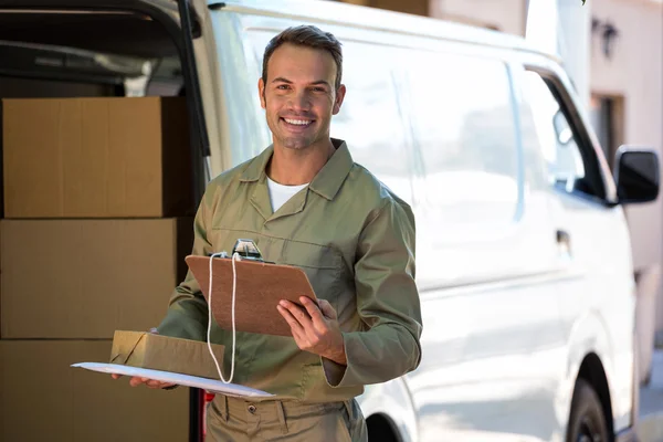 Delivery man holding cardboard box and clipboard