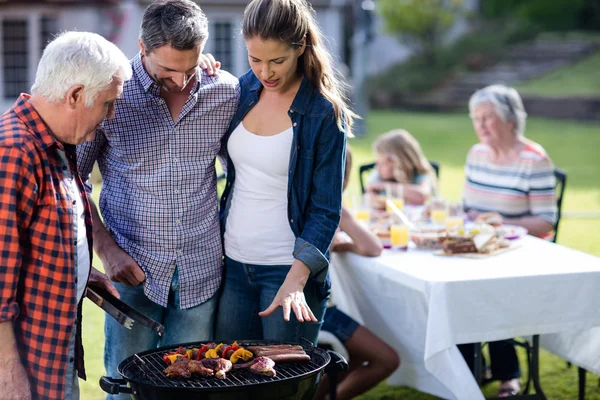 Couple and senior man at barbecue grill