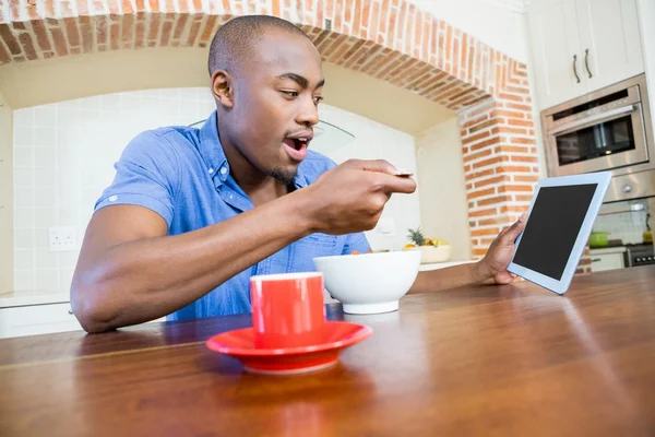Man having breakfast using tablet