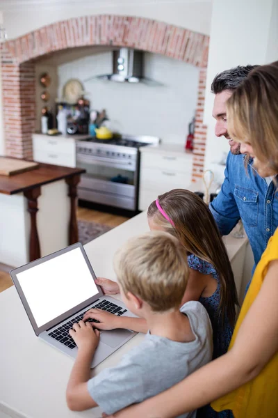 Parents and kids using laptop in kitchen