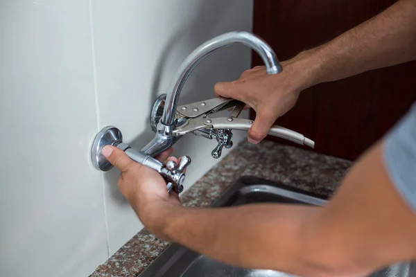Hands of man fixing faucet with wrench