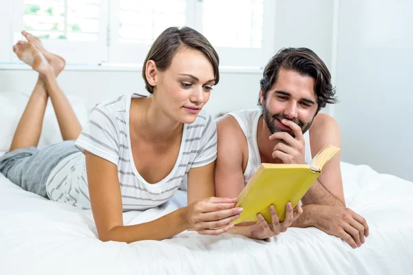 Couple reading book on bed