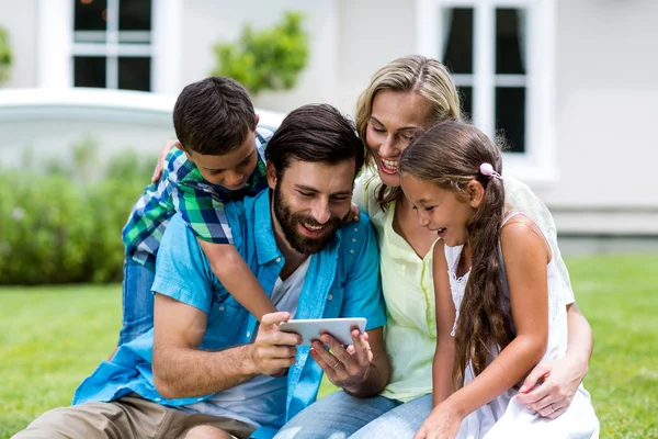 family looking into mobile phone at yard