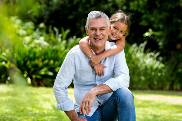 Grandfather and grandaughter smiling at yard