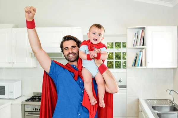 Father in superhero costume lifting son