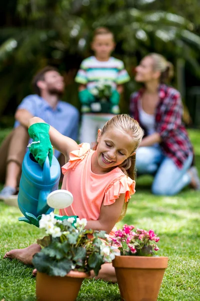 Girl watering flower pots in yard