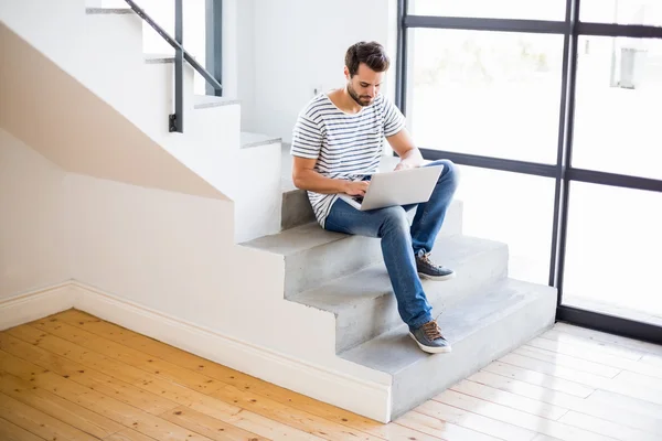 Man sitting on steps using laptop