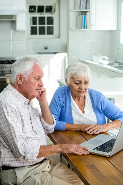 Serious retired couple using laptop