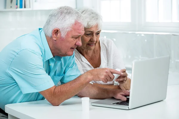 Senior couple with bottles using laptop