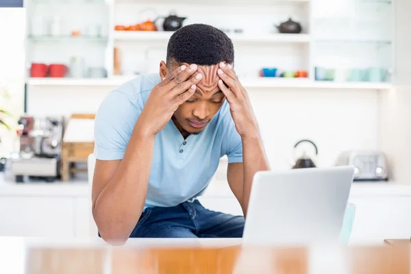 Tense man in kitchen with laptop