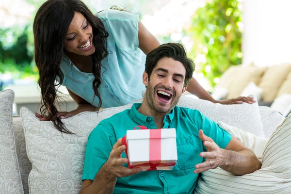 Woman giving surprise gift to man
