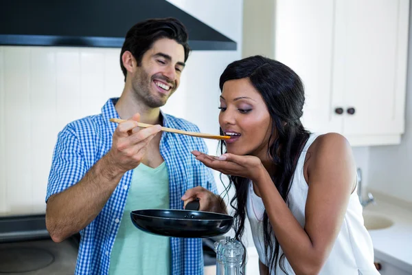 Man feeding woman while cooking